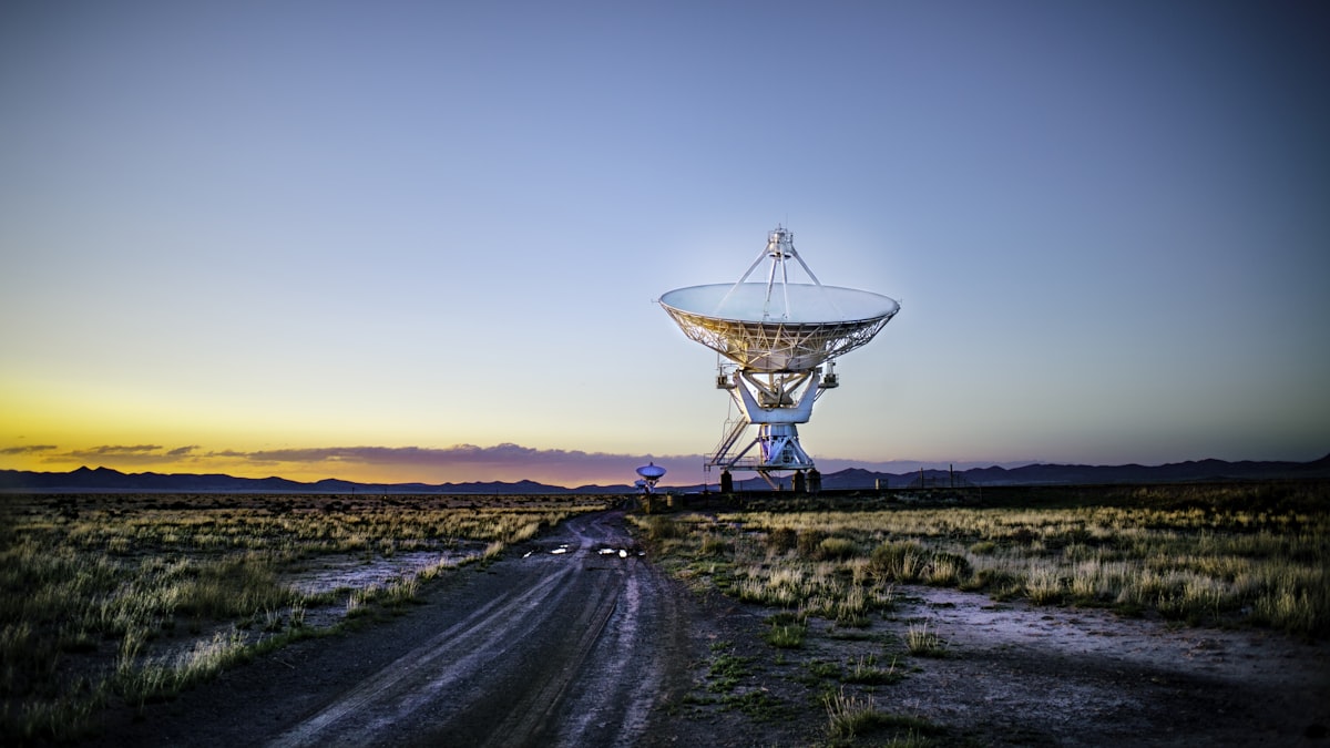 Large radio antenna dish in open terrain at dusk