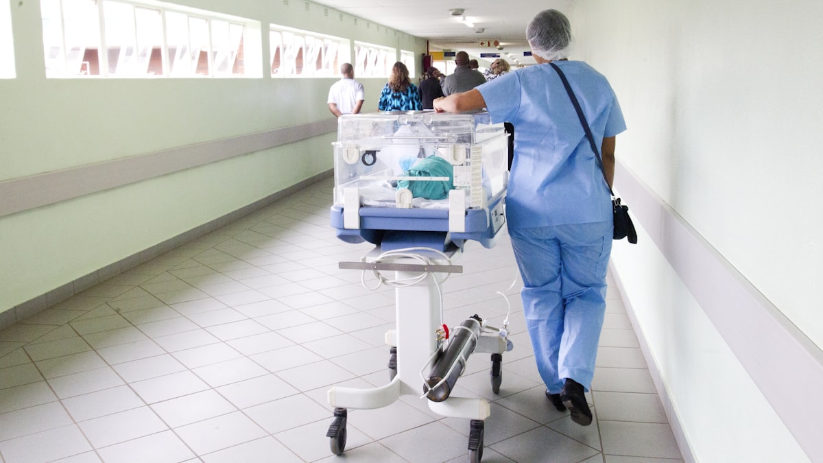 Clinician moving equipment along a hospital ward corridor