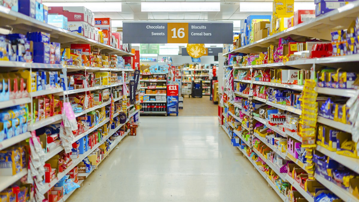 Stocked supermarket aisle seen down the centre line